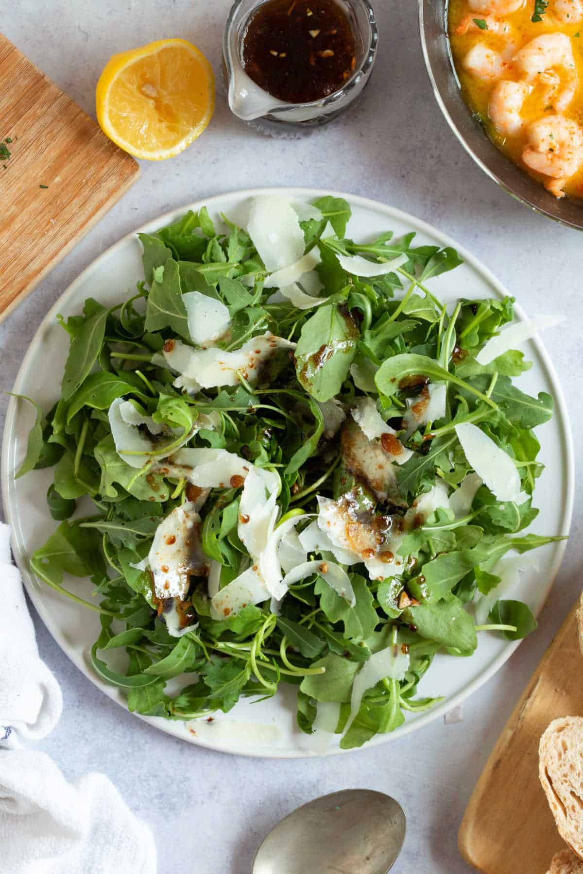 Rocket salad with Parmesan shavings on a white serving platter.