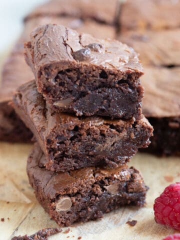 A stack of air fryer chocolate brownies with raspberries on the side.
