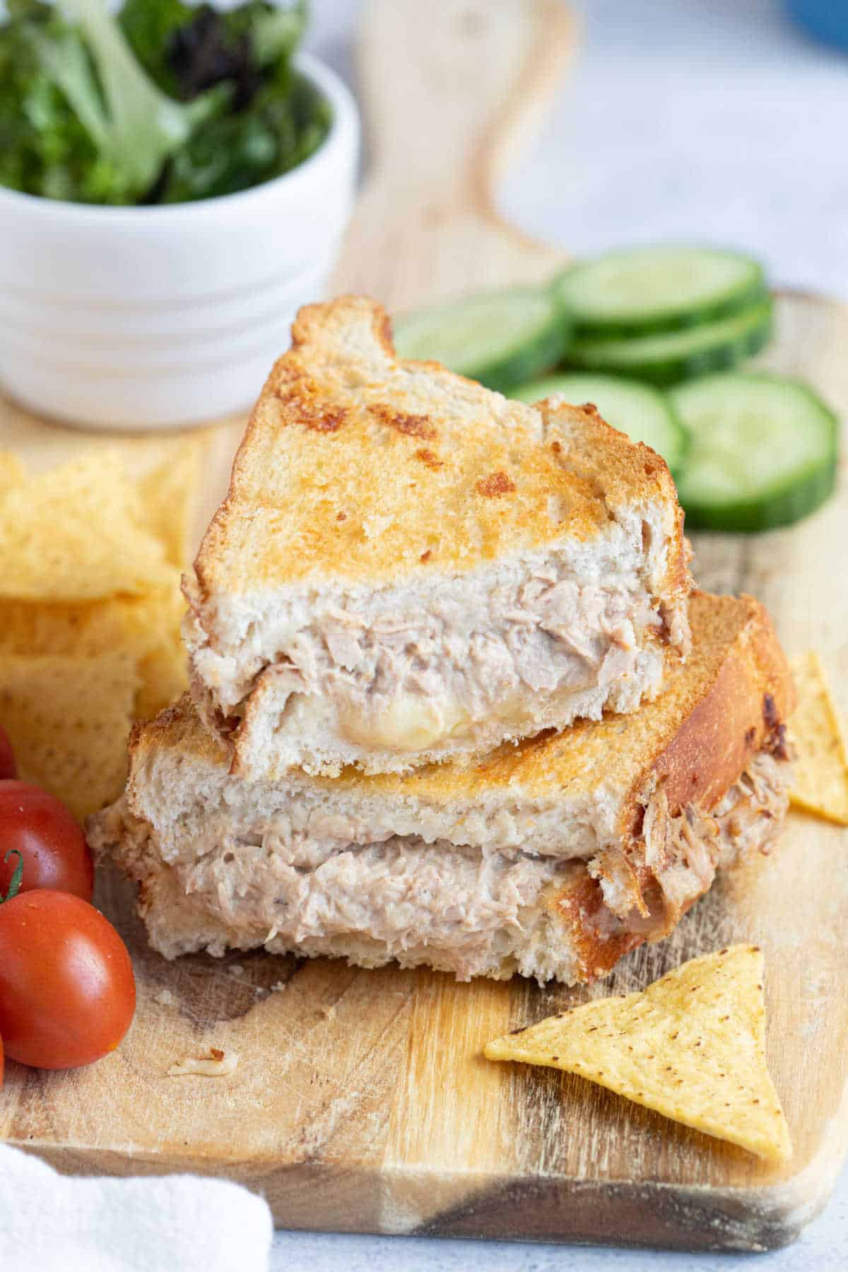 An air fried tuna melt sandwich cut in half and served with tortilla chips and tomatoes.
