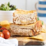 Air fryer tuna mwlt sandwich on a wooden board with salad and crisps.