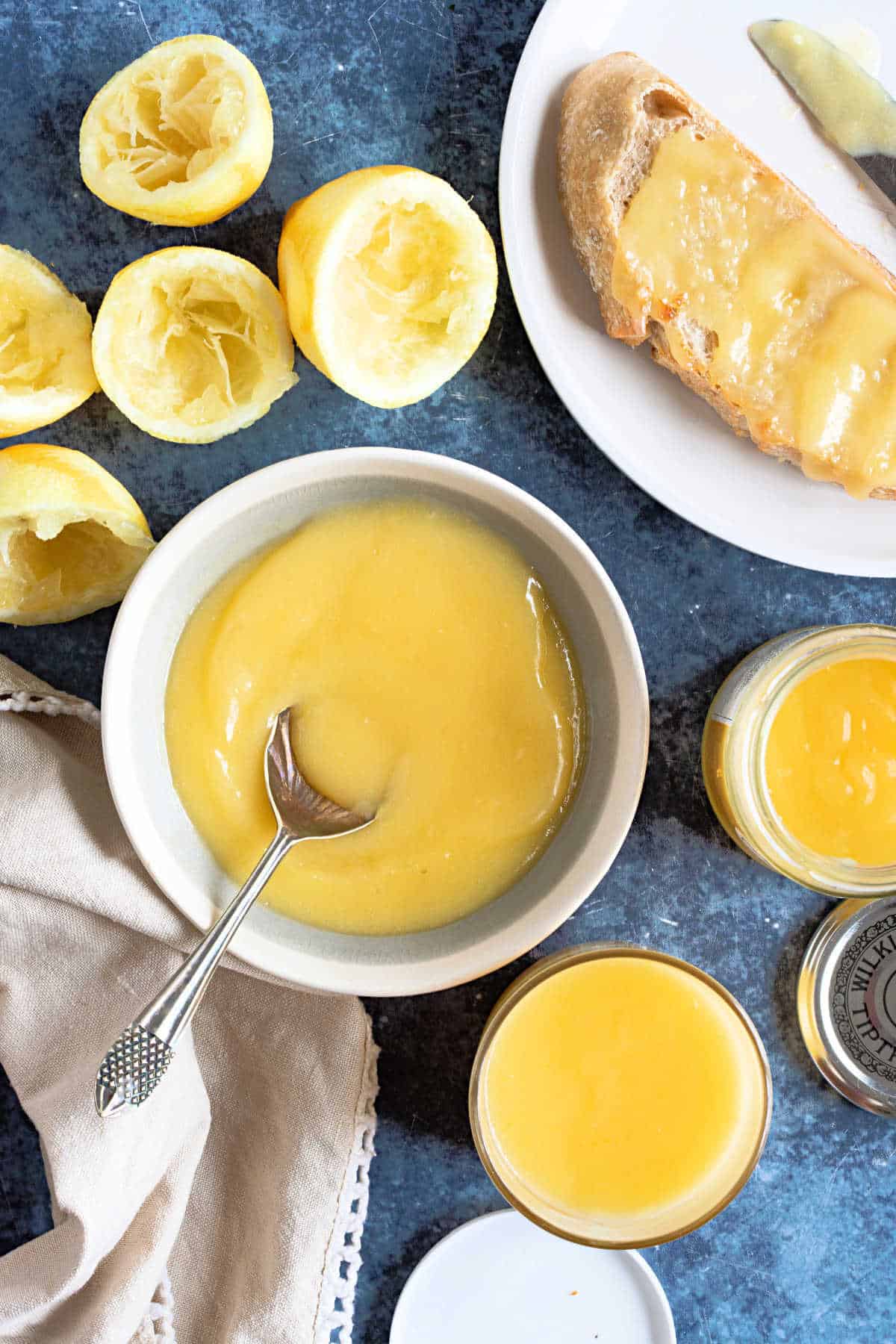 A bowl of lemon curd with lemons around it.