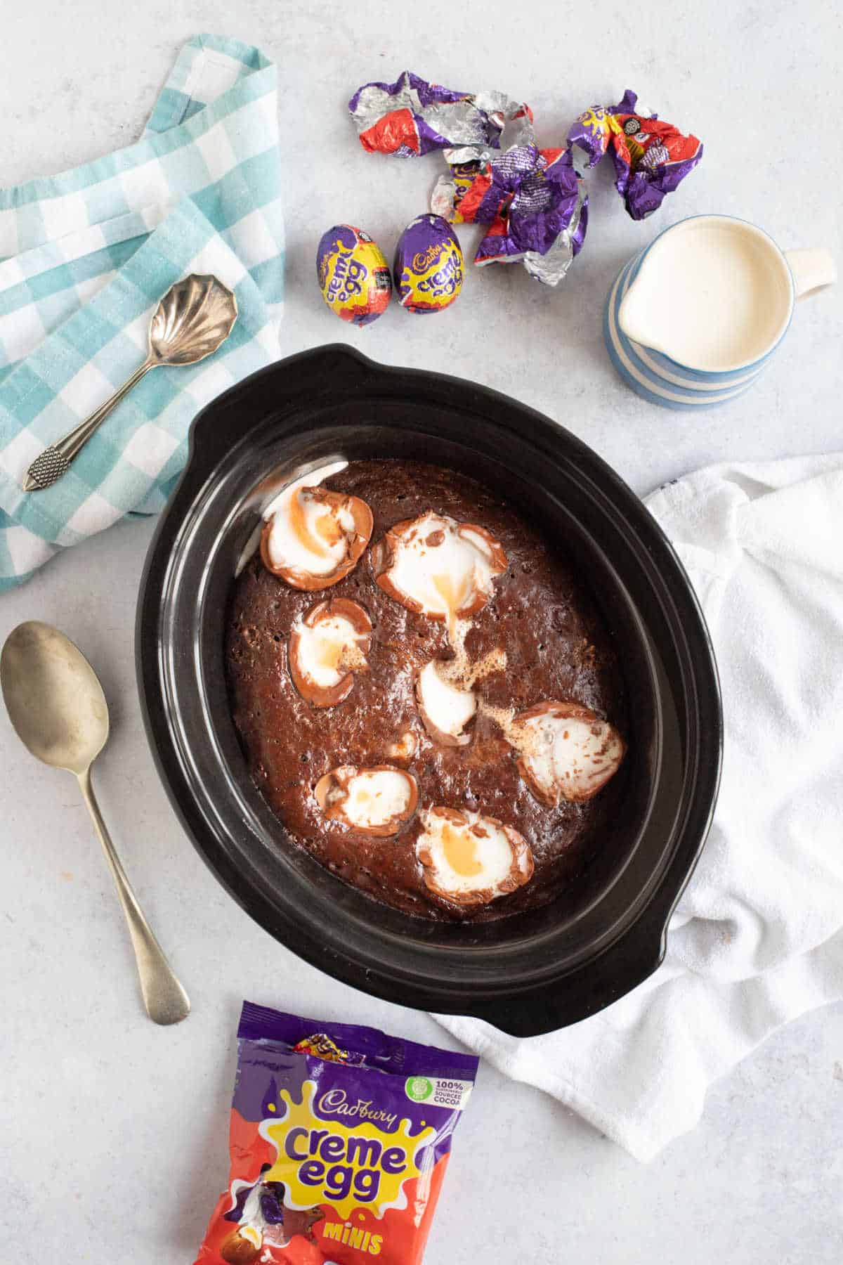 Slow cooker chocolate pudding in a slow cooker basin, with creme egg wrappers around the outside.