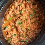 Slow cooker pork ragu in a black crock pot.