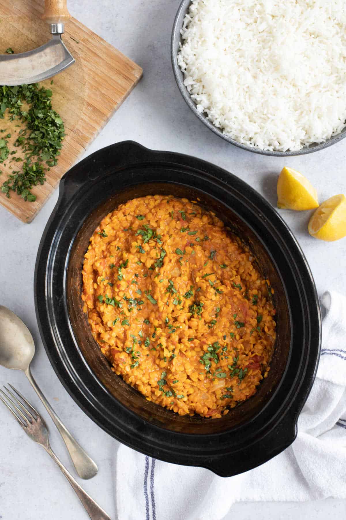 Slow cooker red lentil dahl in a crock pot with a side of rice.