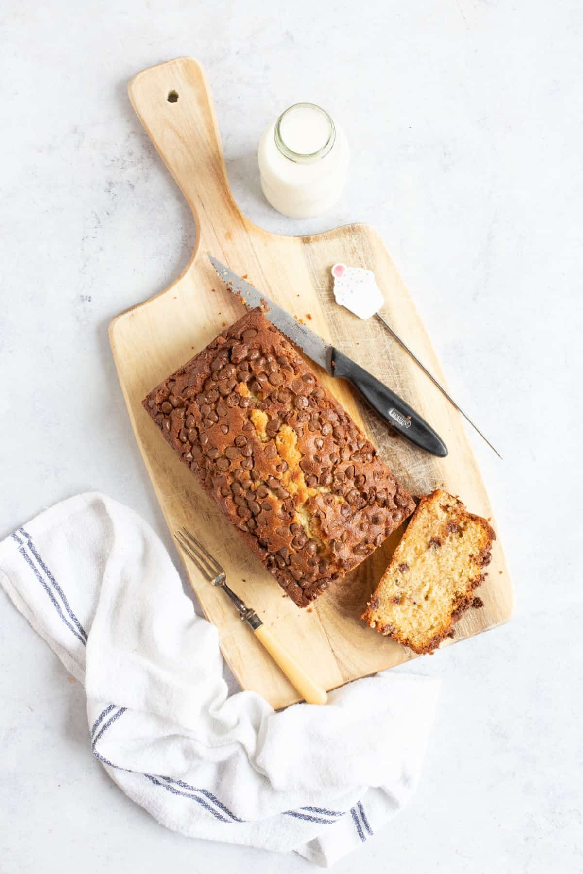 Air fryer banana bread on a wooden board with a slice cut off.