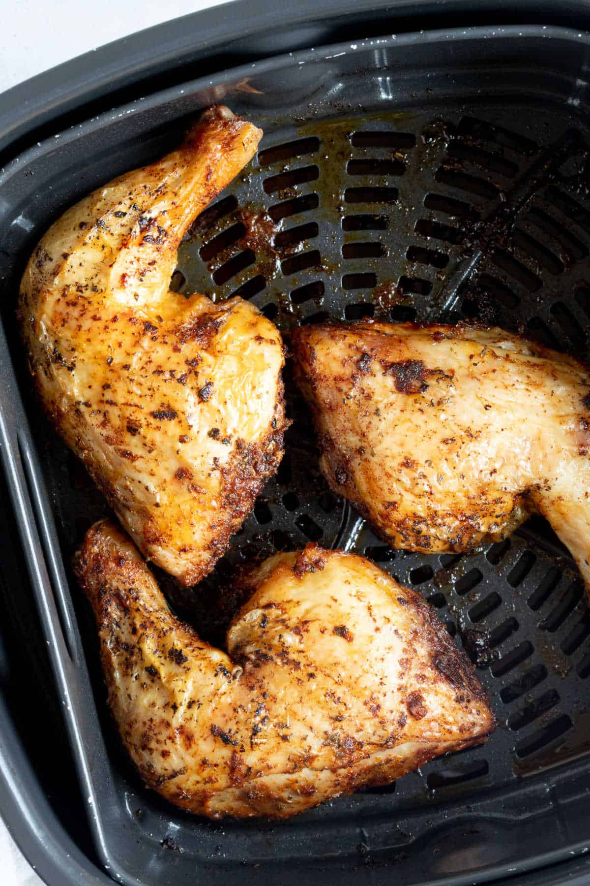 Crispy chicken legs in an air fryer basket.