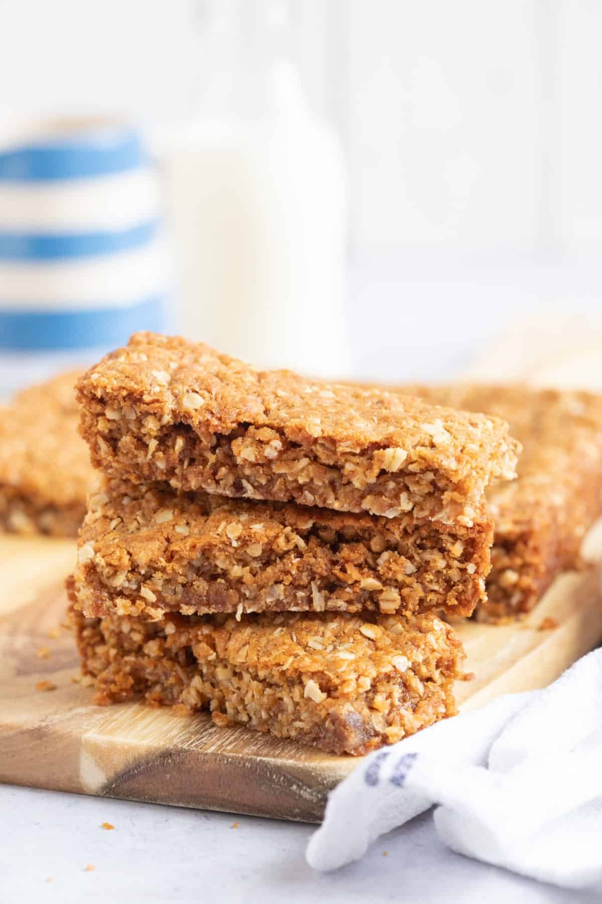 A stack of Anzac slices on a wooden board.