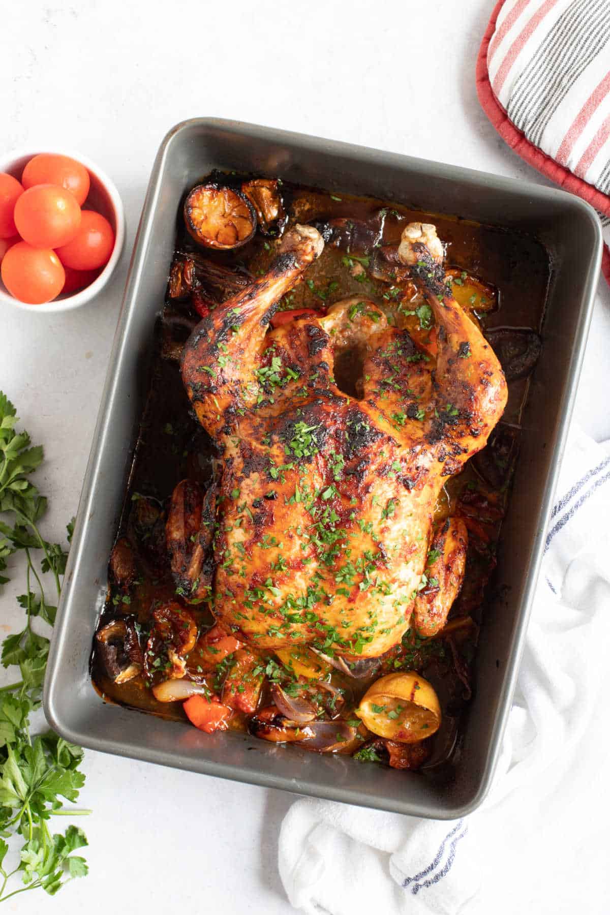 Cooked harissa roast chicken in a roasting tin.