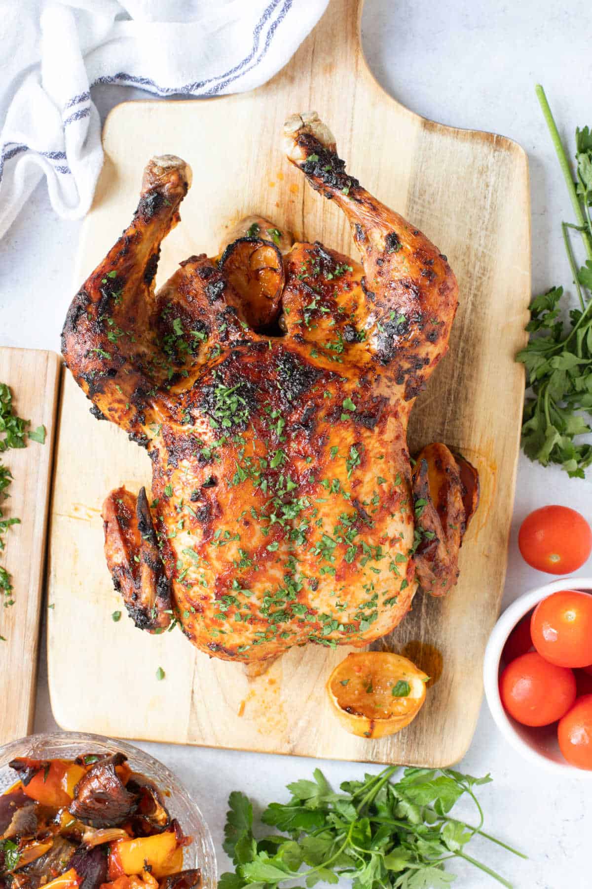 Harissa roast chicken on a wooden board with lemons.