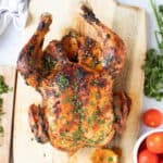 Harissa roast chicken on a wooden carving board.