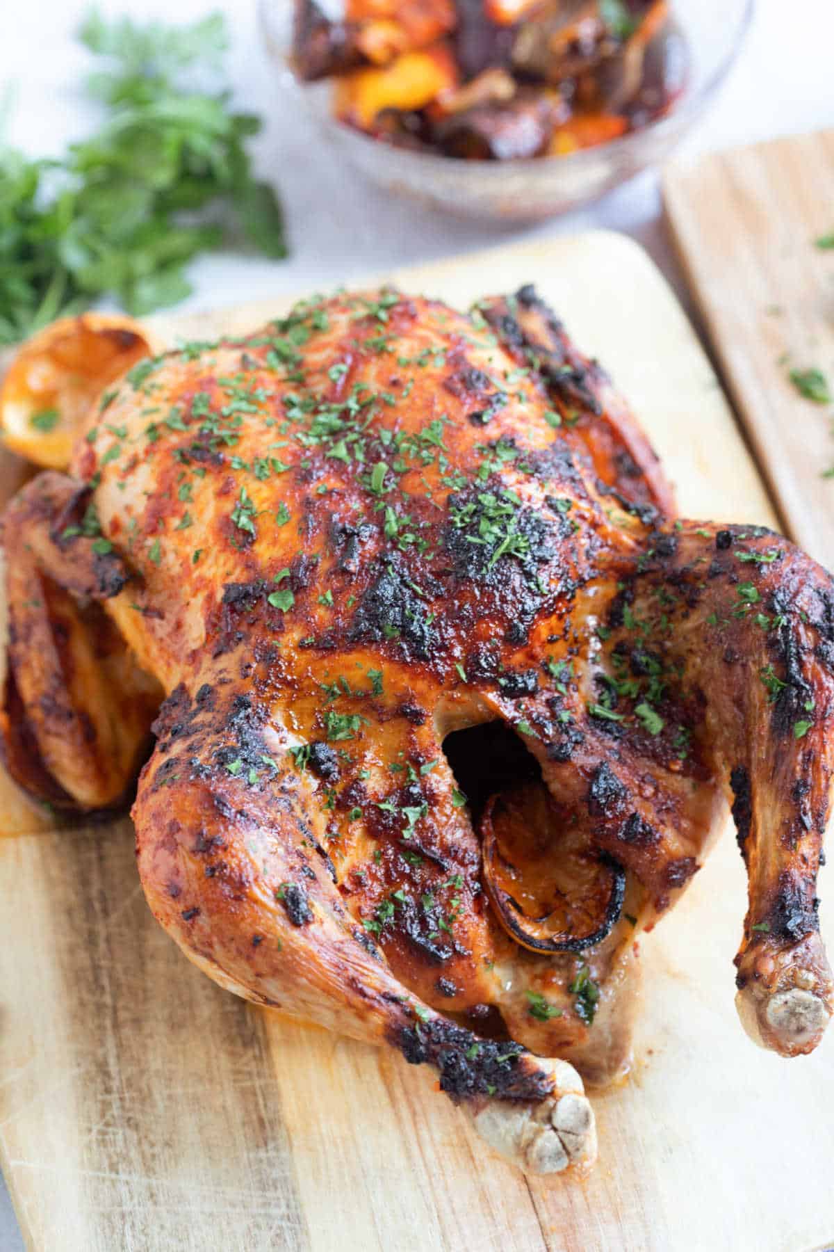 Spicy whole roast chicken on a board for carving.