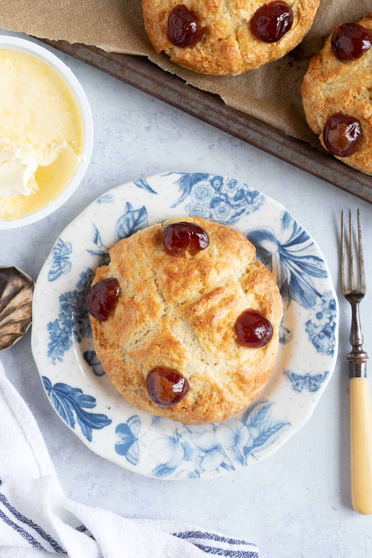 A Victoria scone on a blue and white tea plate with a pot of clotted cream on the side.