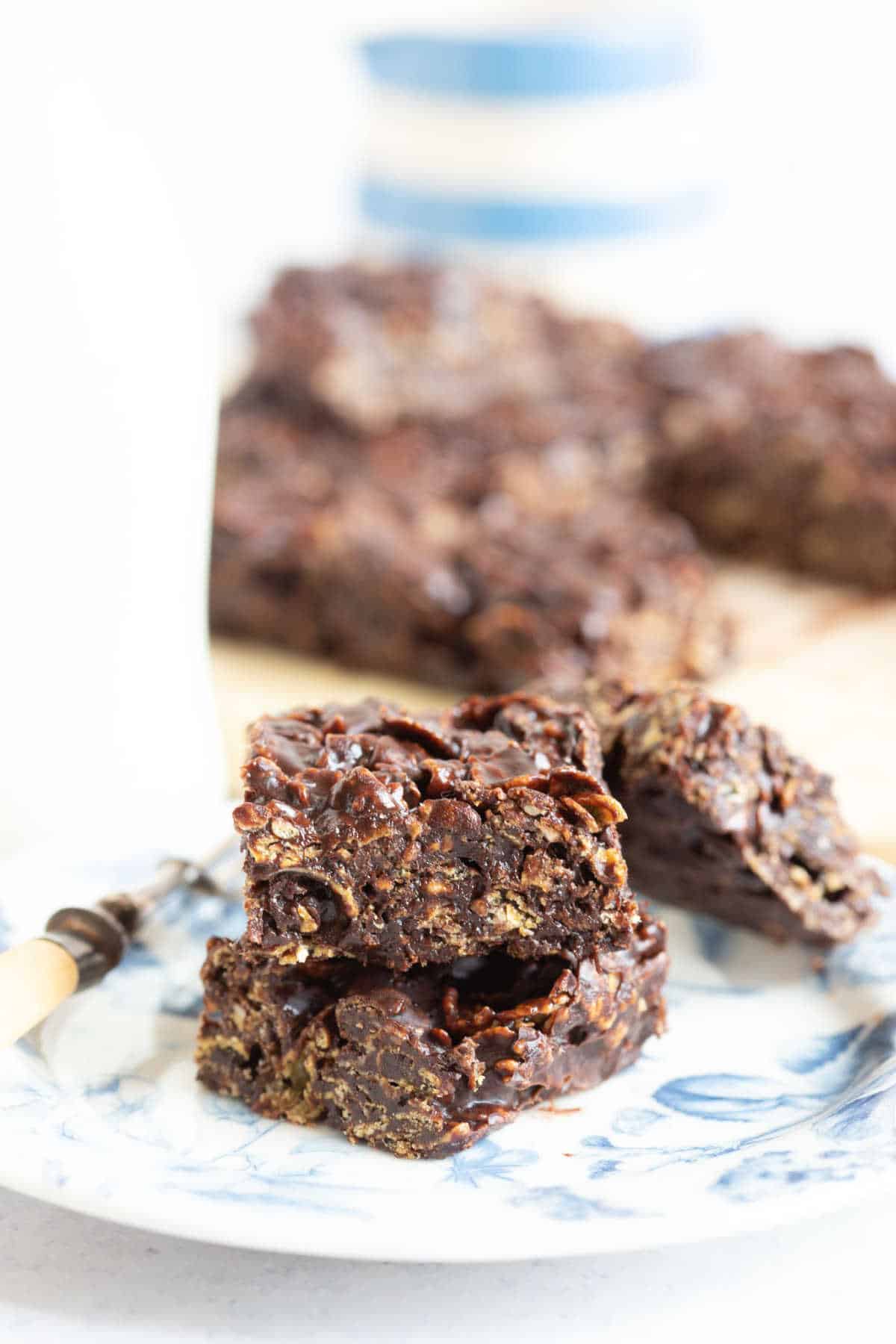 Chocolate cracknell bars on a plate with a glass of milk behind.