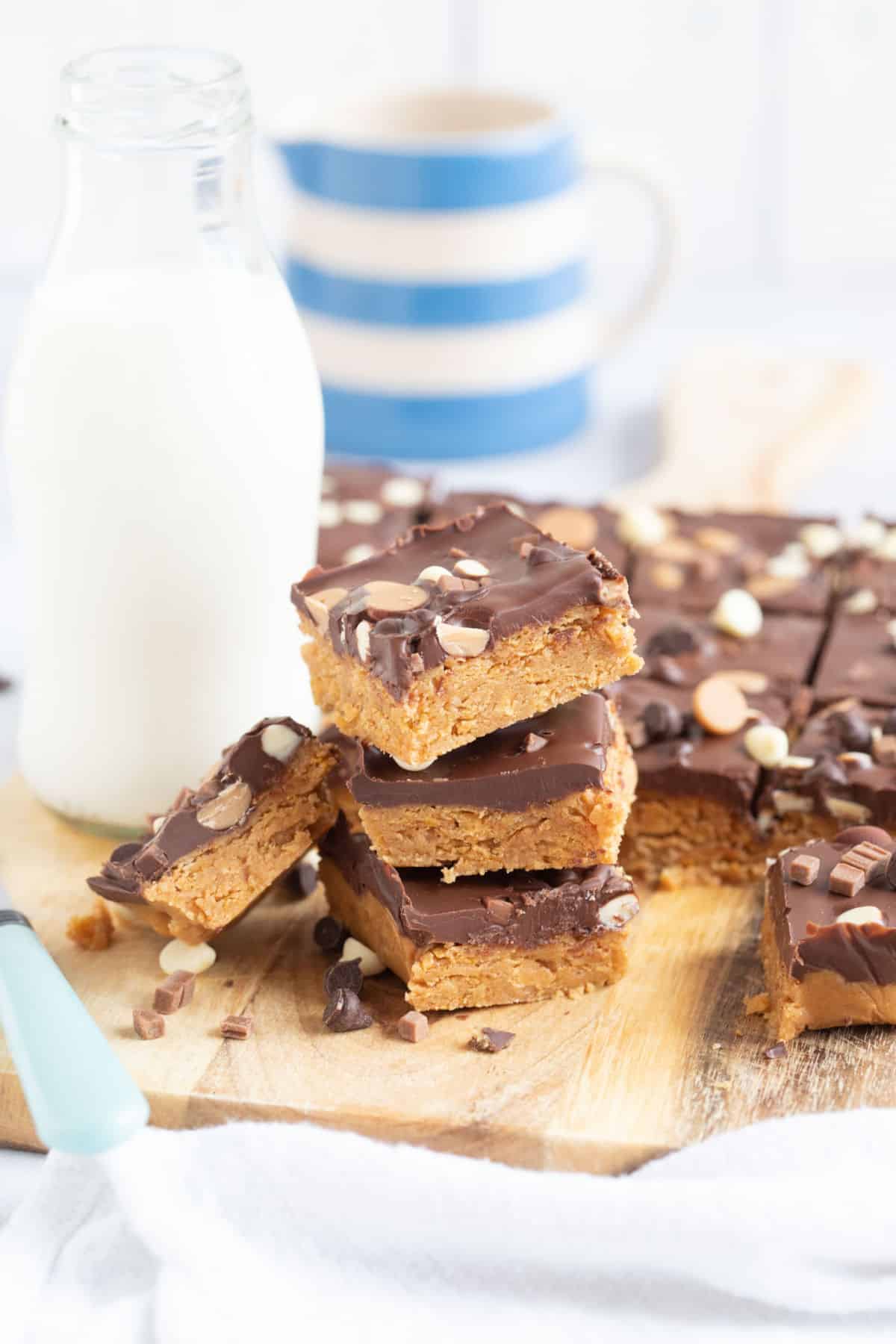 A stack of no bake chocolate peanut butter bars on a wooden board.