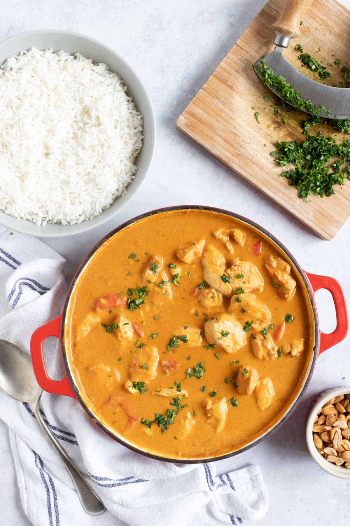 Peanut butter chicken curry in a red pan garnished with coriander.