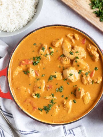 Peanut butter chicken satay curry in a red pan with coriander.