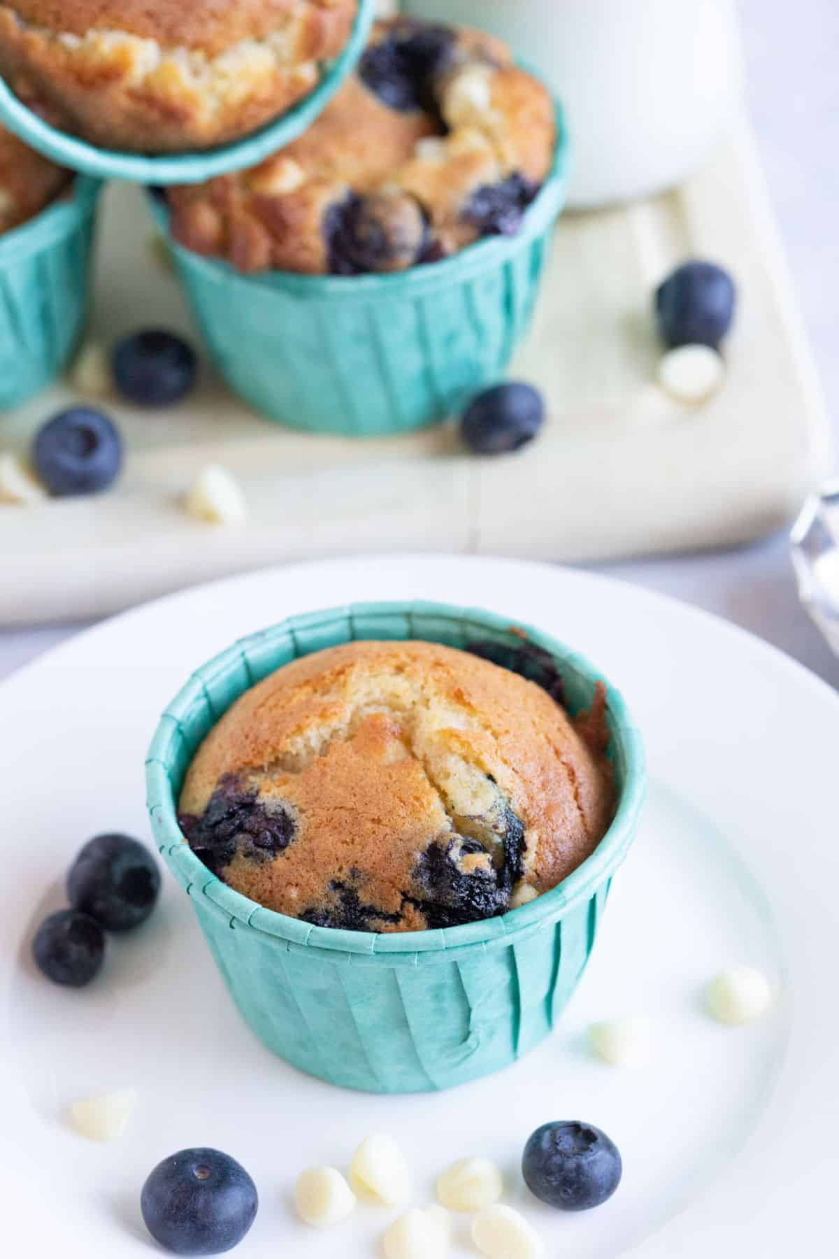An air fryer muffin on a plate with blueberries and white chocolate chips.