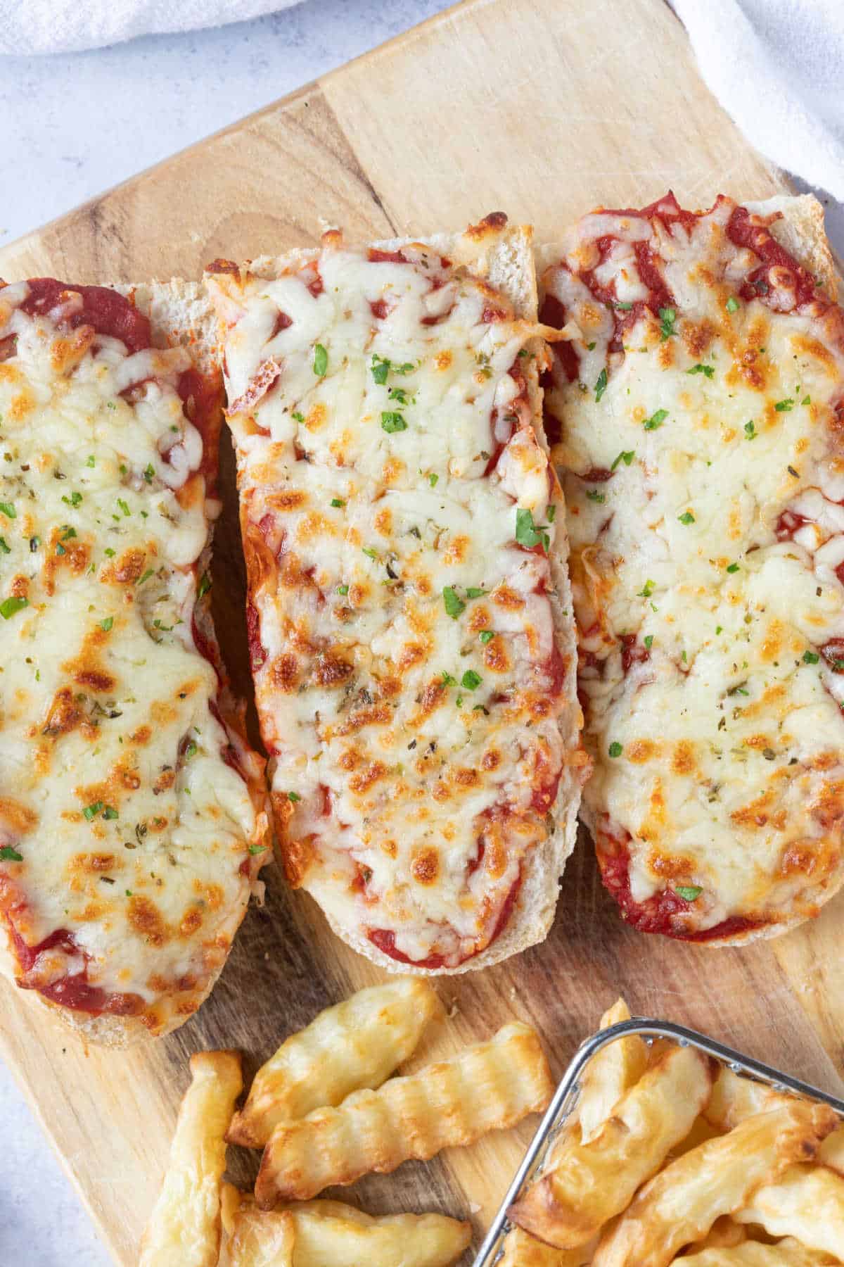 Air fryer French bread pizzas on a wooden board.