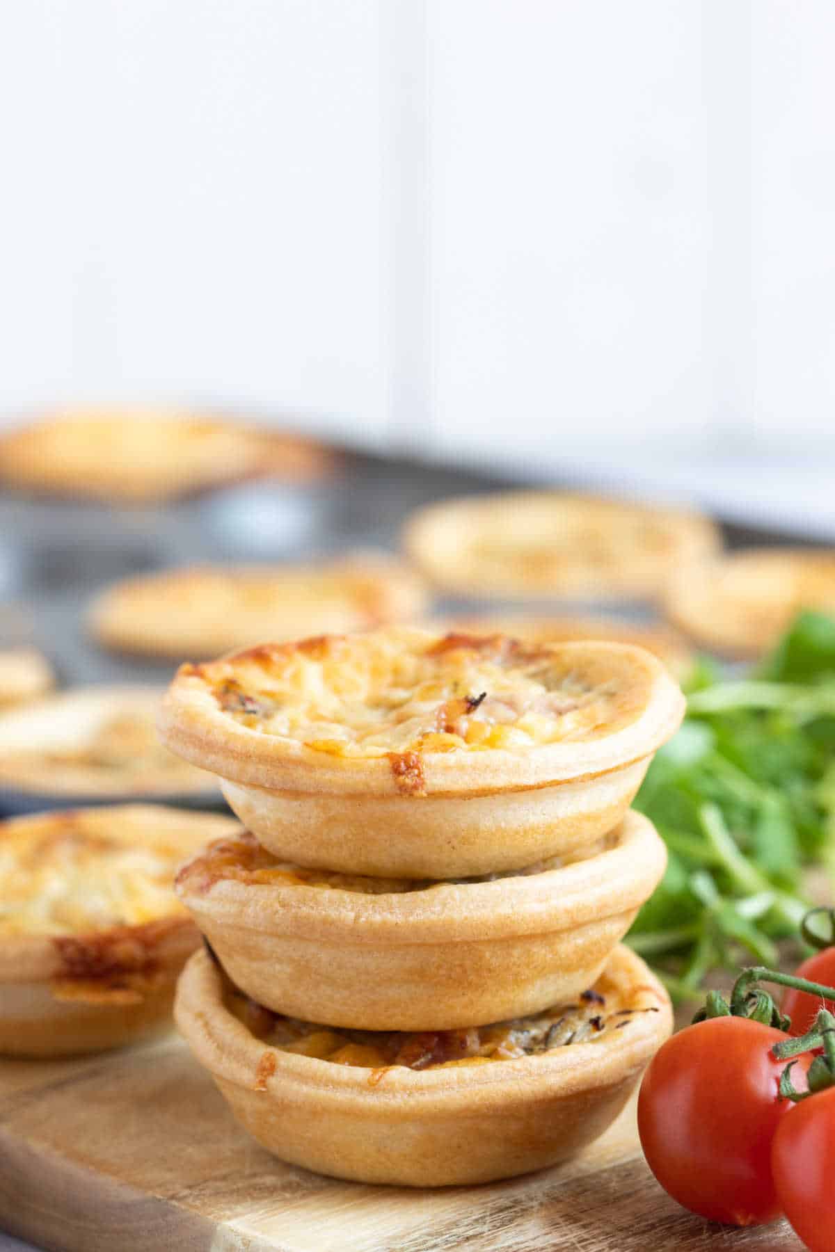 A stack of mini quiches with cherry tomatoes.