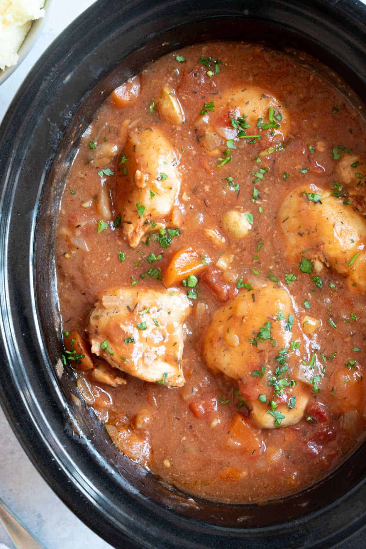 Slow cooker chicken chasseur in a black slow cooker basin.