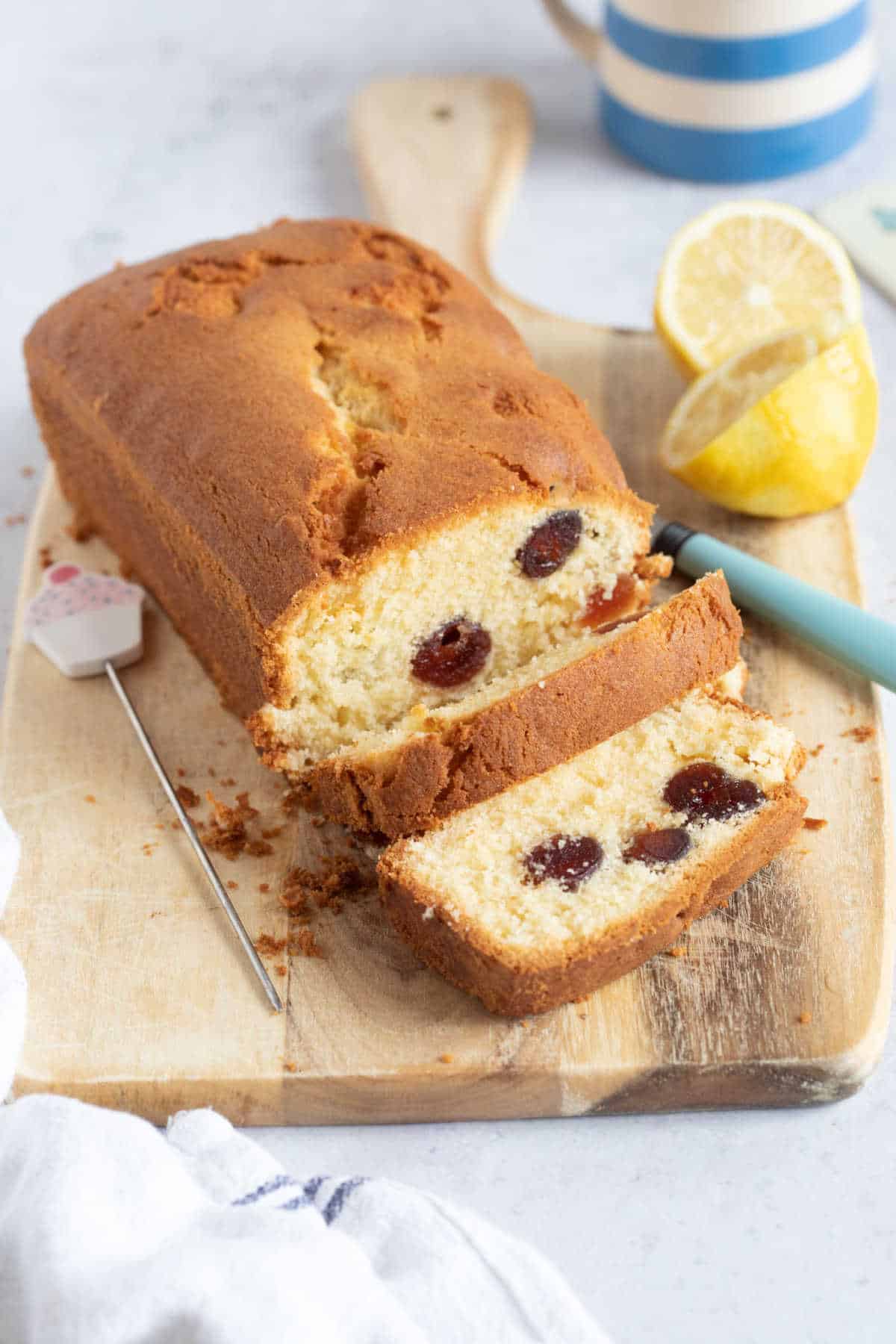 Air fryer cherry Madeira cake on a wooden board with two slices cut.