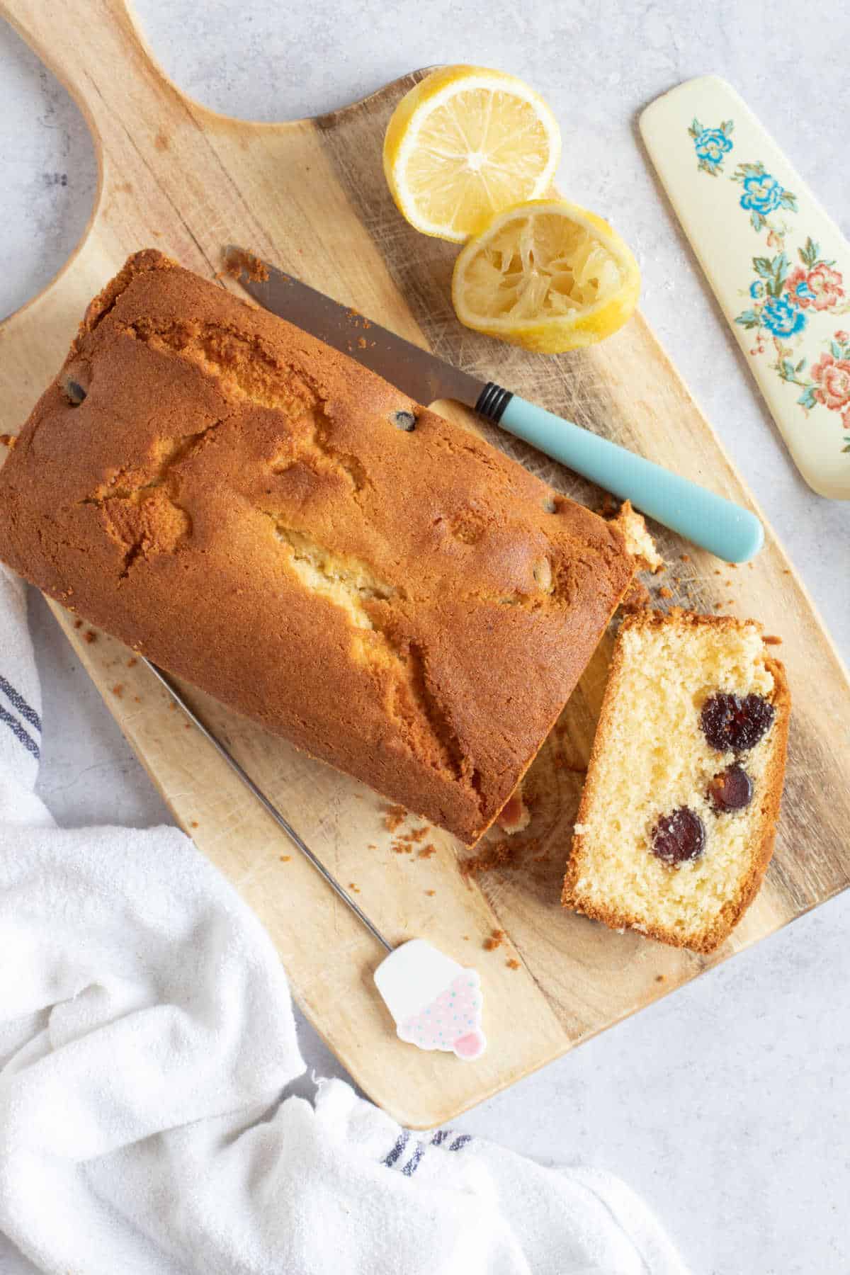 Air fryer cherry madeira cake on a wooden board with a slice cut.