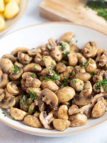 Golden brown air fryer garlic mushrooms on a plate.