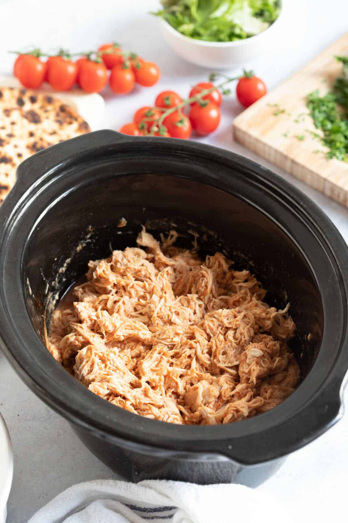 Slow cooker BBQ pulled chicken in a black slow cooker basin.