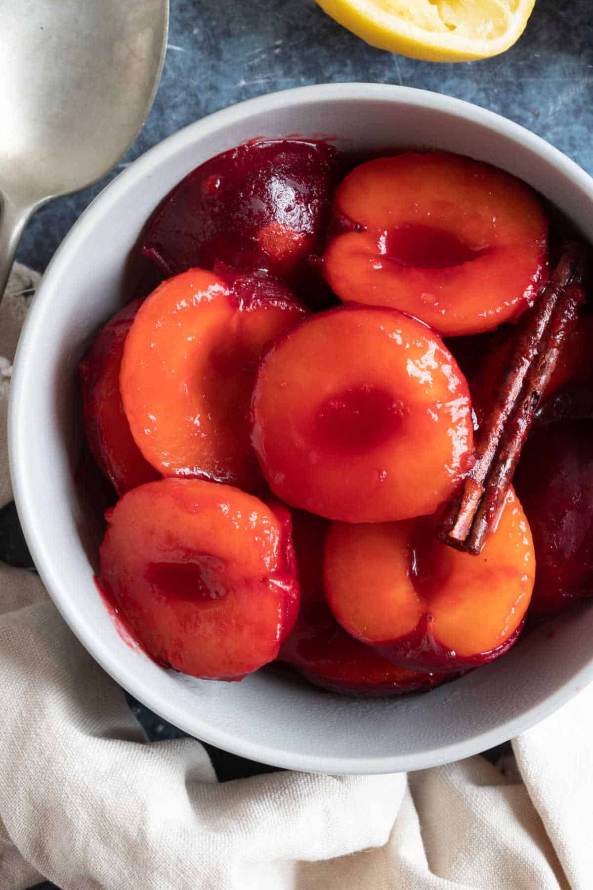 Stewed plums with cinnamon stick in a bowl.