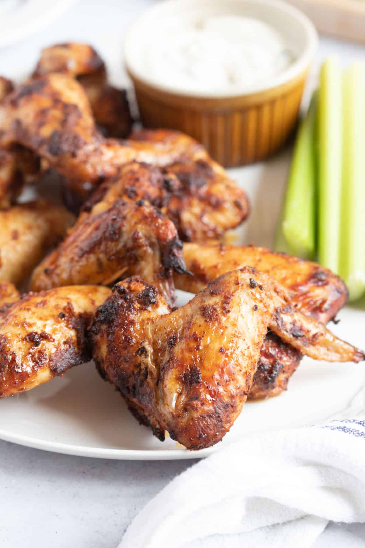 Crispy air fryer chicken wings on a white serving platter with celery sticks and sour cream dip.