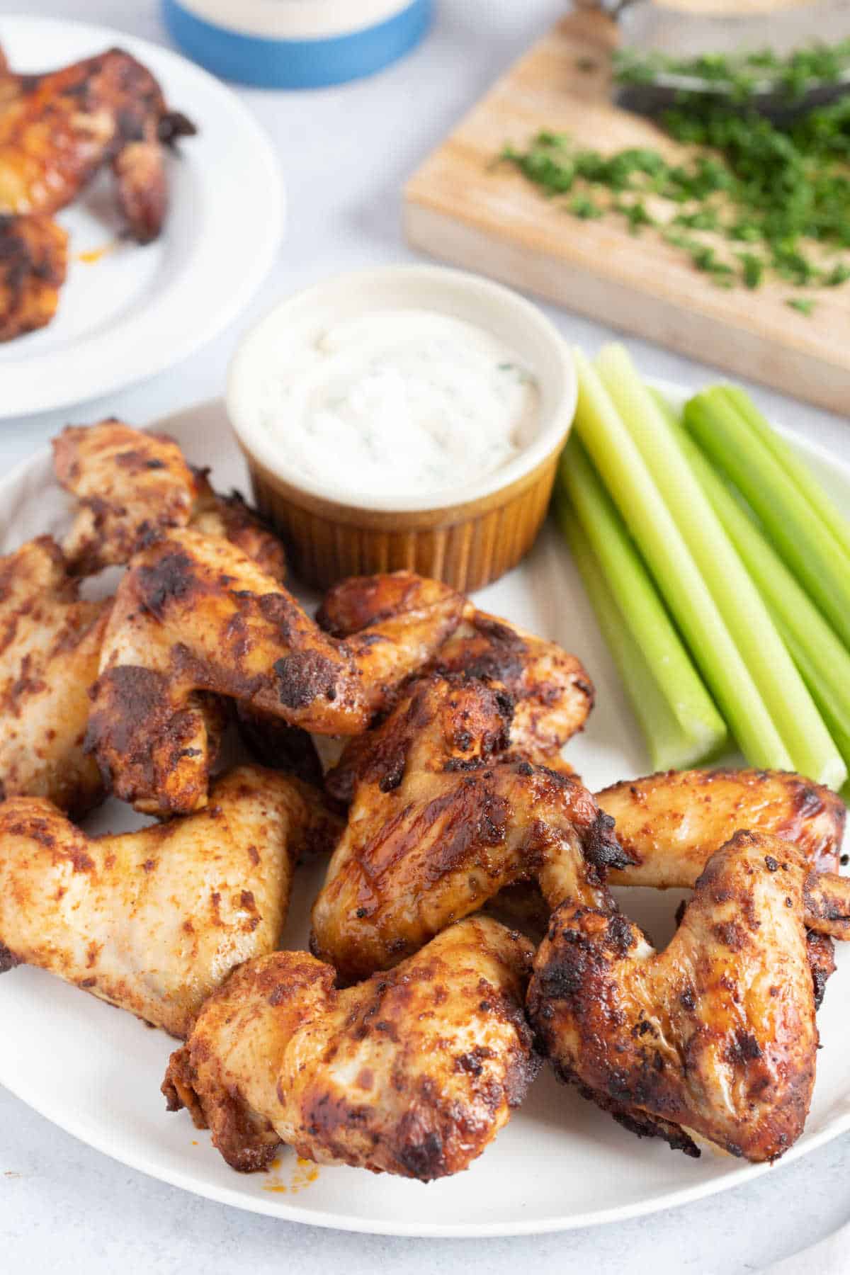 A plate of spicy air fryer chicken wings with celery sticks.