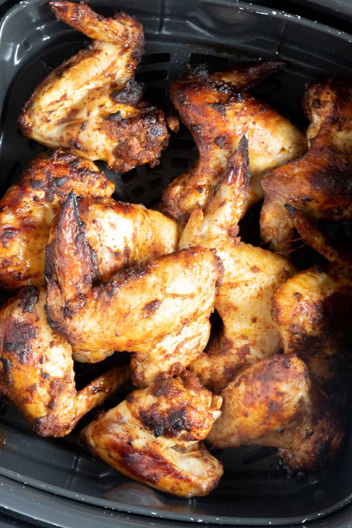 Crispy chicken wings in an air fryer basket.