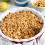 Apple and pear crumble in a red pie dish.