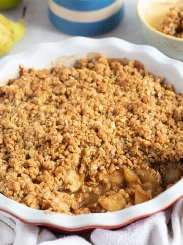 Apple and pear crumble in a red pie dish.