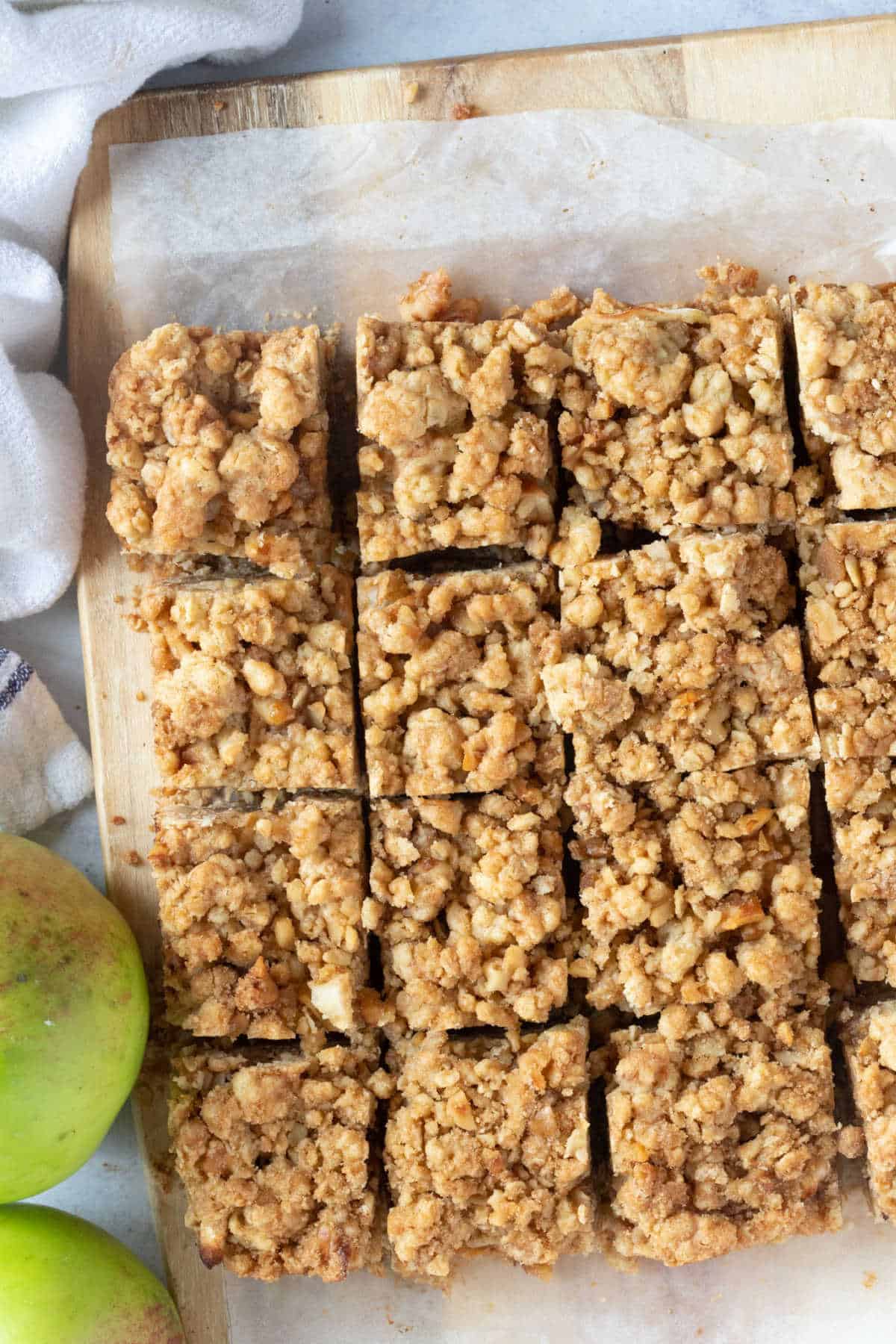 Apple crumble bars cut into slices on a wooden board.