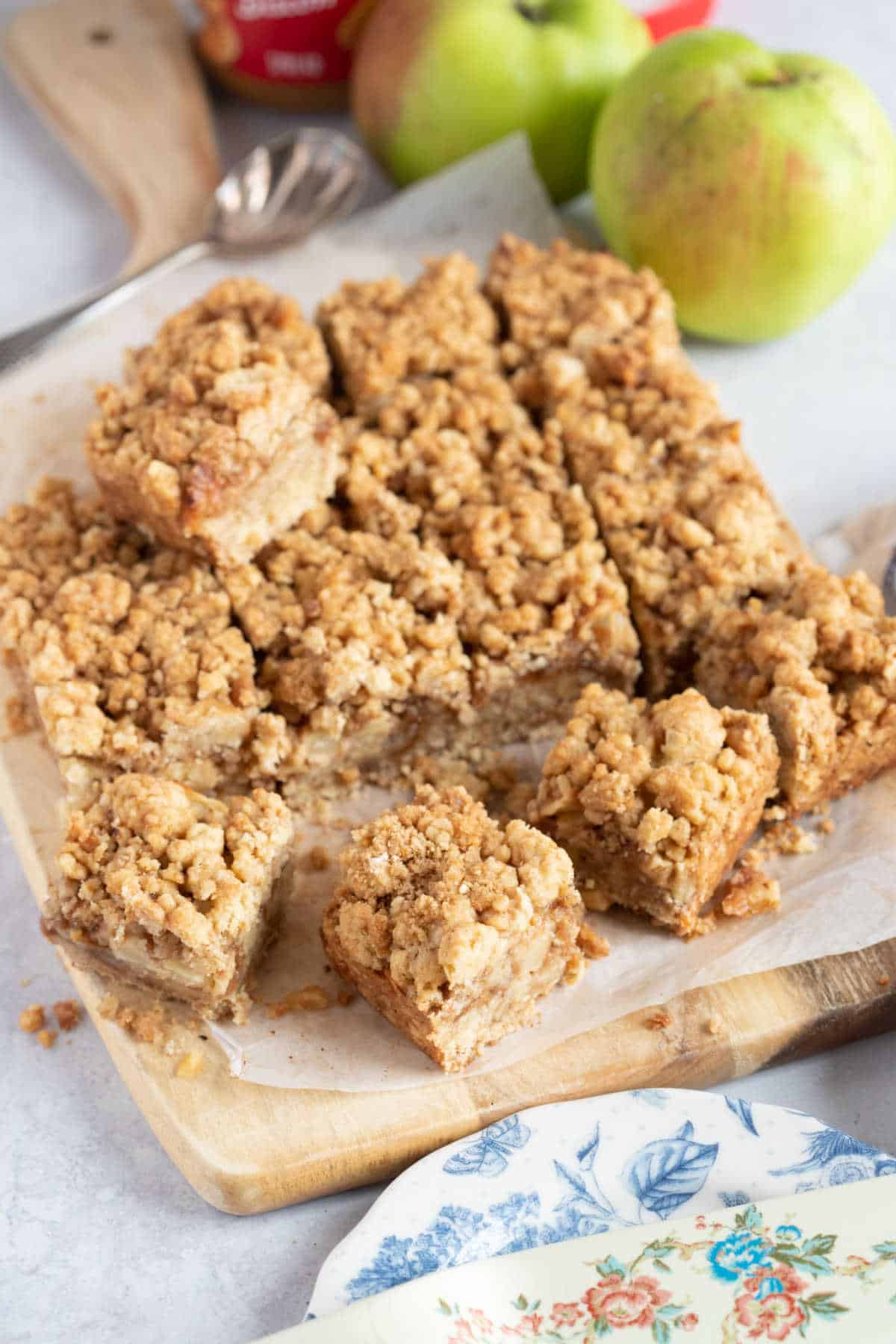 Apple crumble bars on a presentation board with apples in the background.