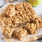 Apple crumble bars cut into slices on a wooden board.