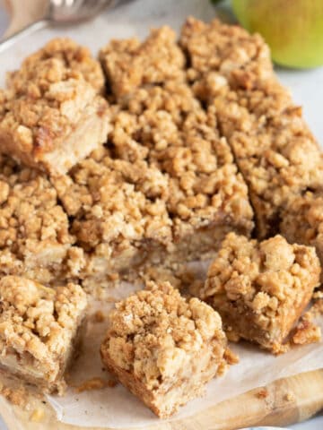Apple crumble bars cut into slices on a wooden board.