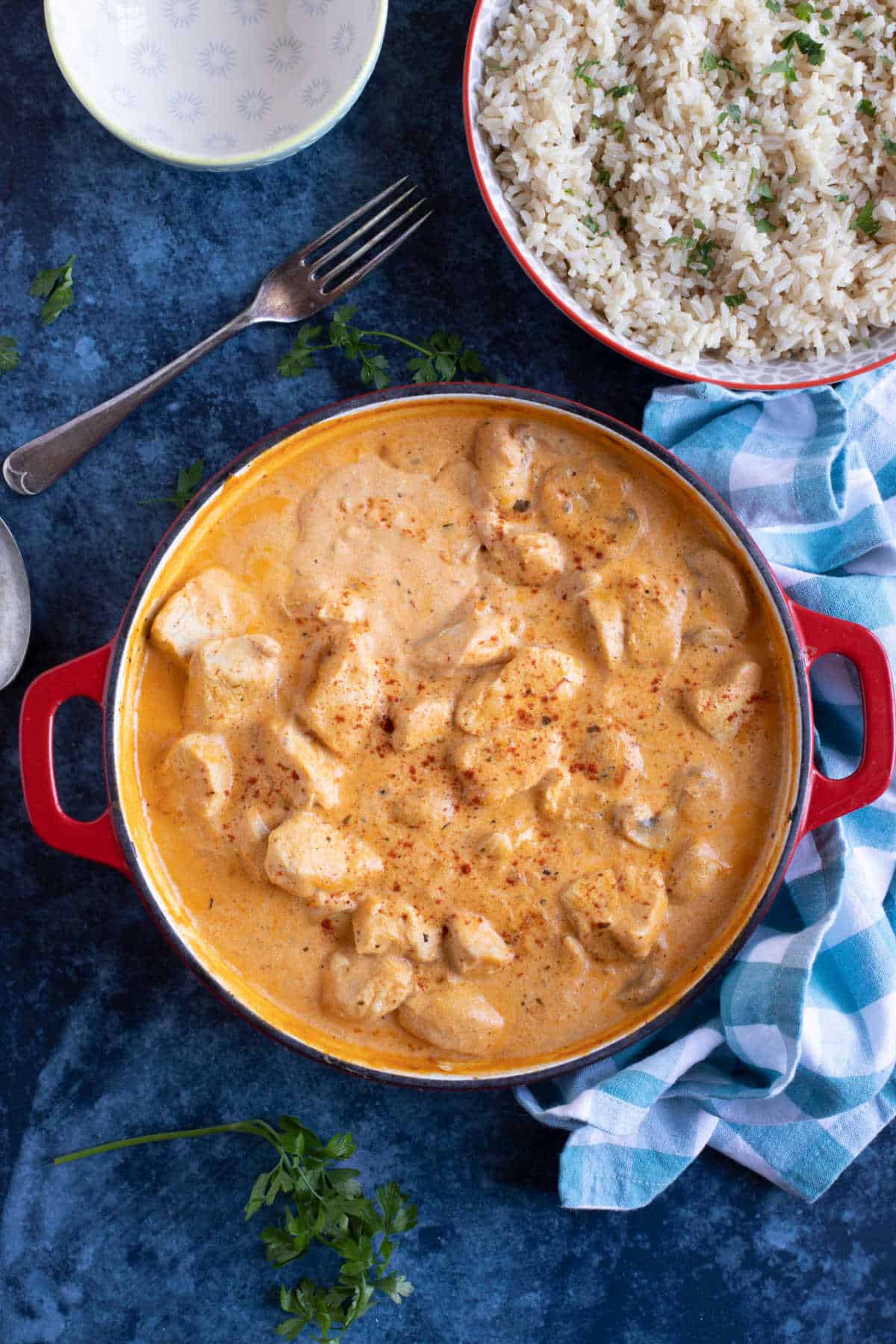 Chicken and mushroom stroganoff in a red pan with a side of rice.