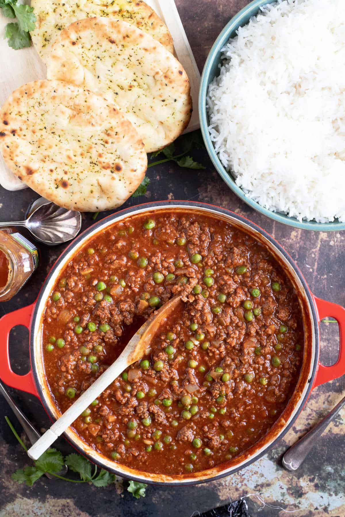 A pan of keema korma with naan bread and rice.