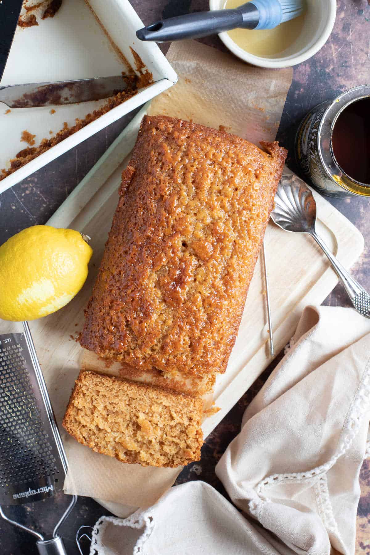 Sticky golden syrup cake on a wooden board with a slice cut off the end.