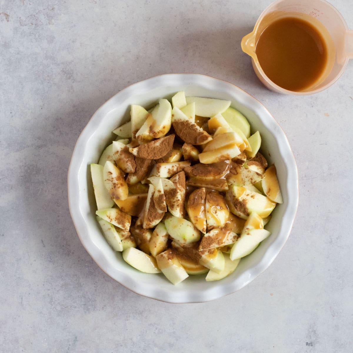 Sliced Bramley apples, cinnamon and toffee sauce in a pie dish.