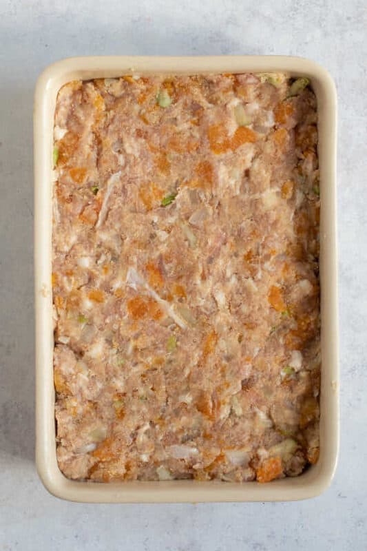 Uncooked apricot and sausage meat stuffing in a baking dish.