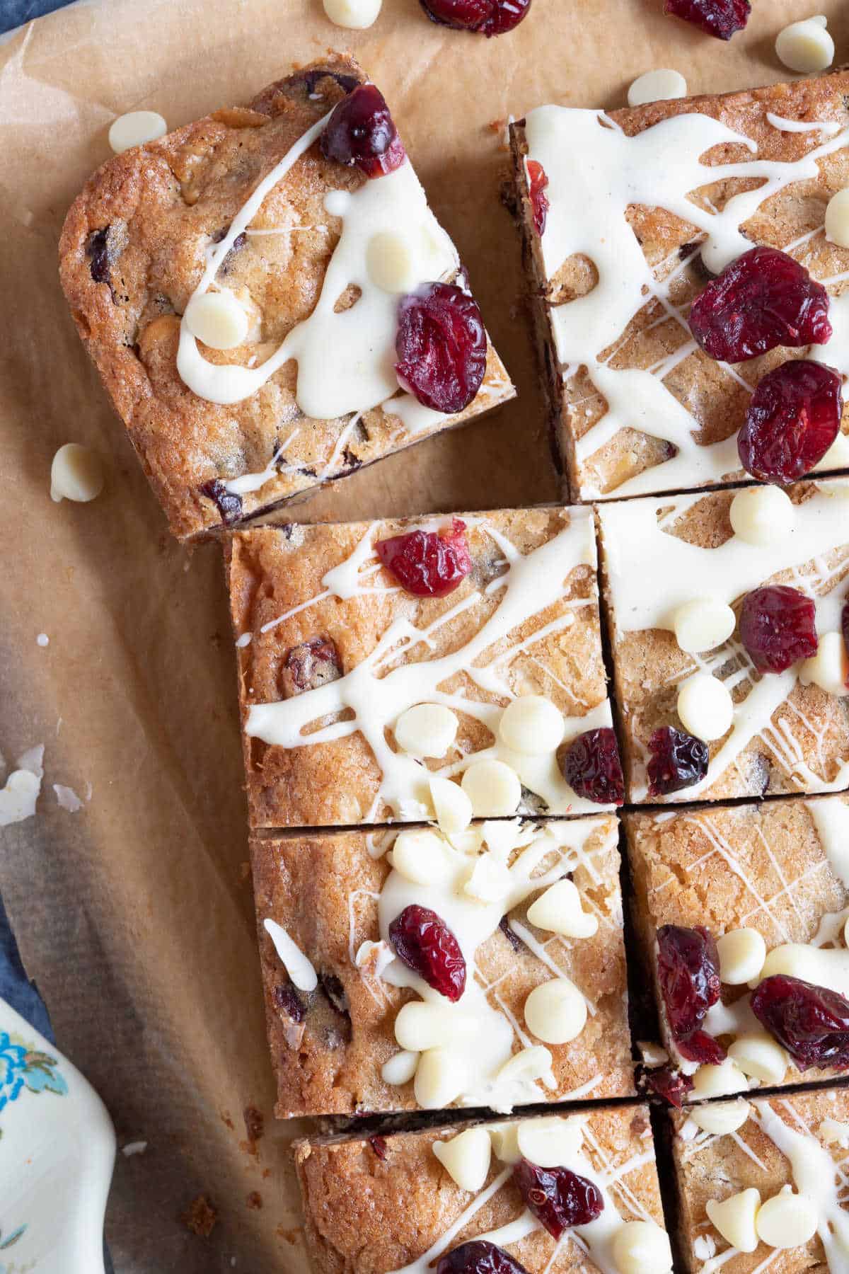 Sliced white chocolate cranberry blondies on a wooden board.