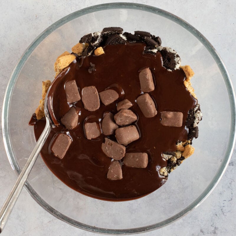 Melted chocolate mixed with crushed biscuits in a bowl.