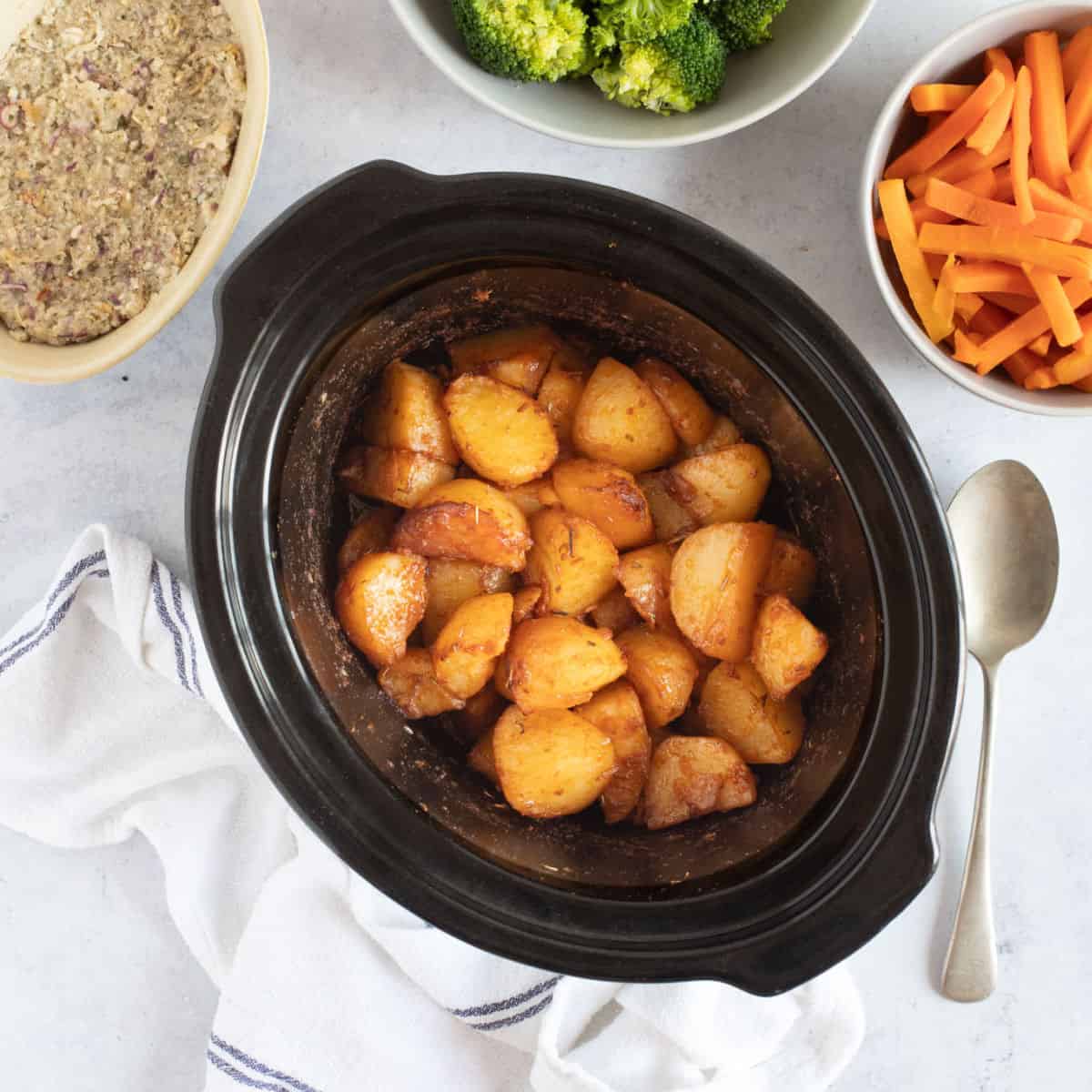 Crispy slow cooker roast potatoes with carrots, broccoli and stuffing.