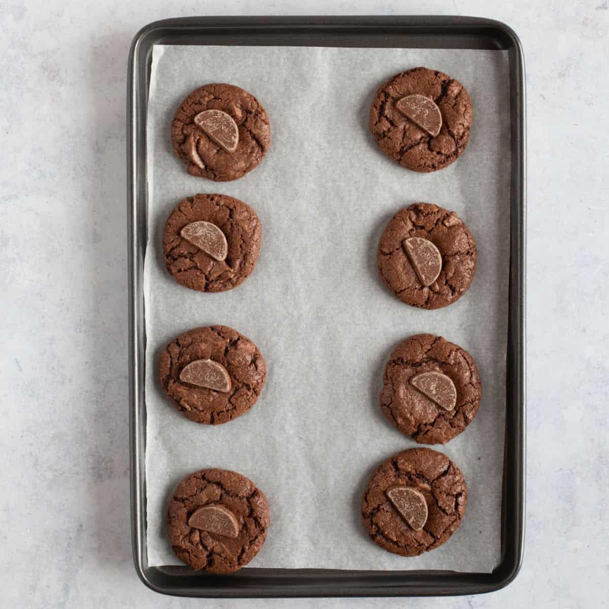 baked chocolate orange cookies on a lined baking tray.