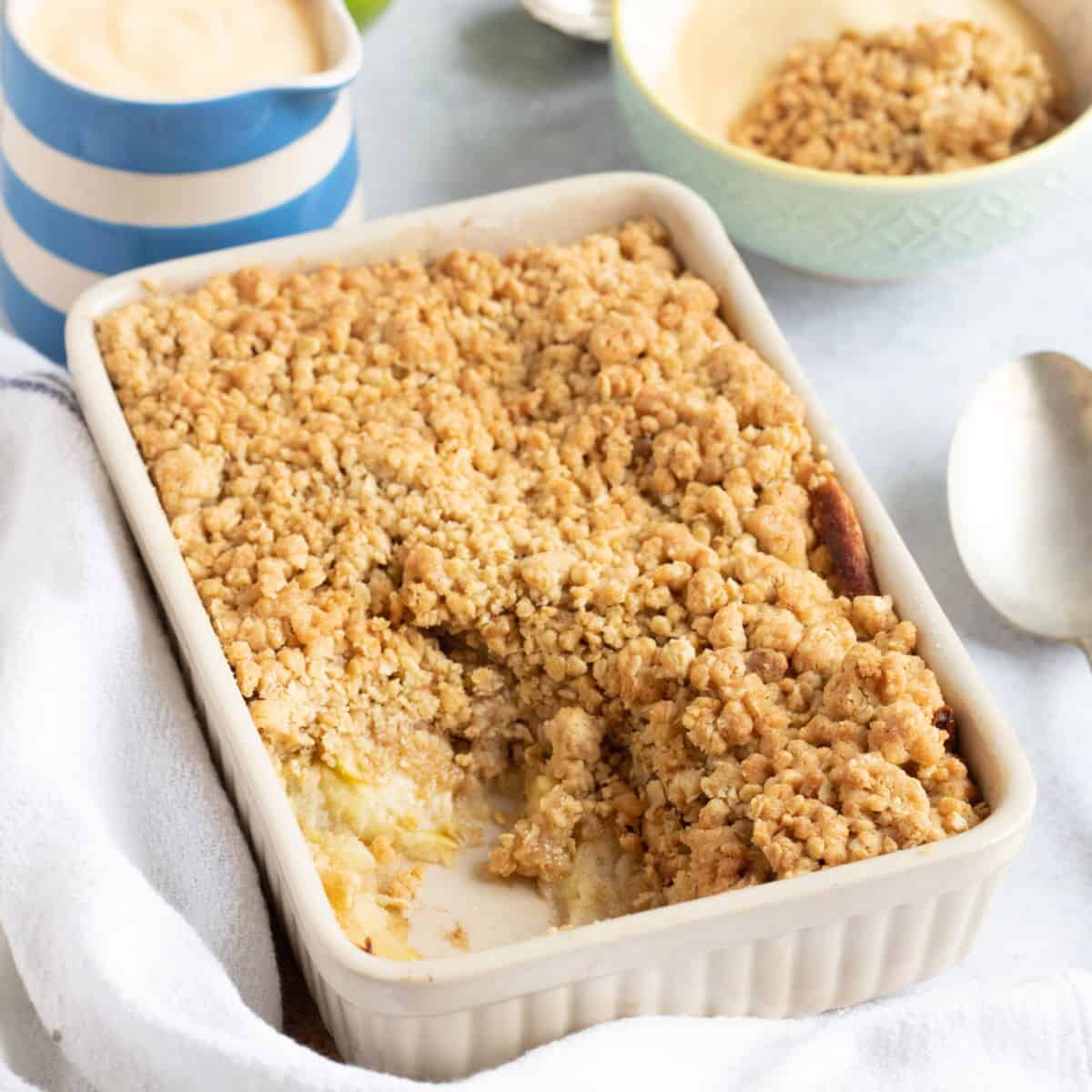 Baked apple crumblewith a jug of custard.