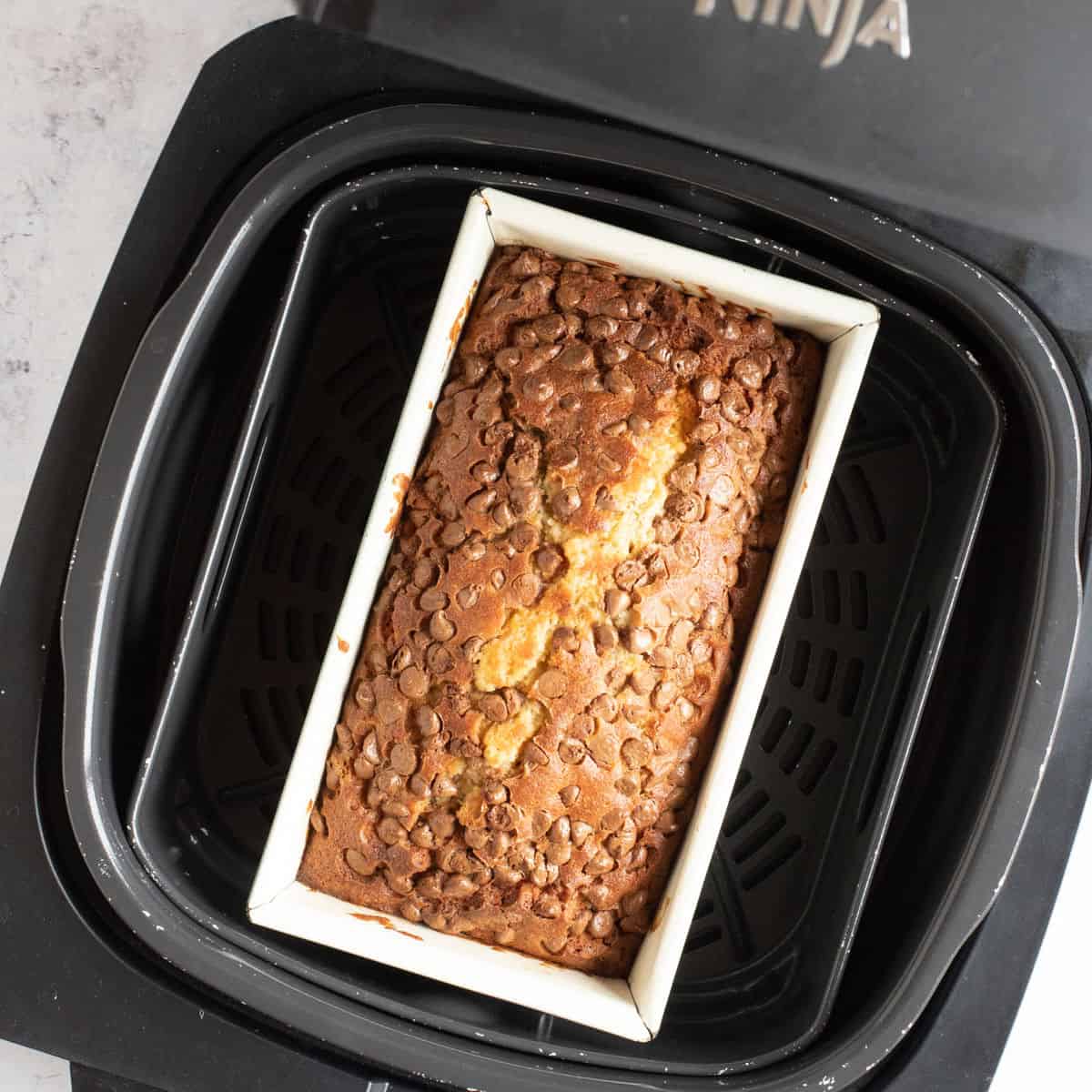 Baked air fryer chocolate chip banana bread in air fryer basket.