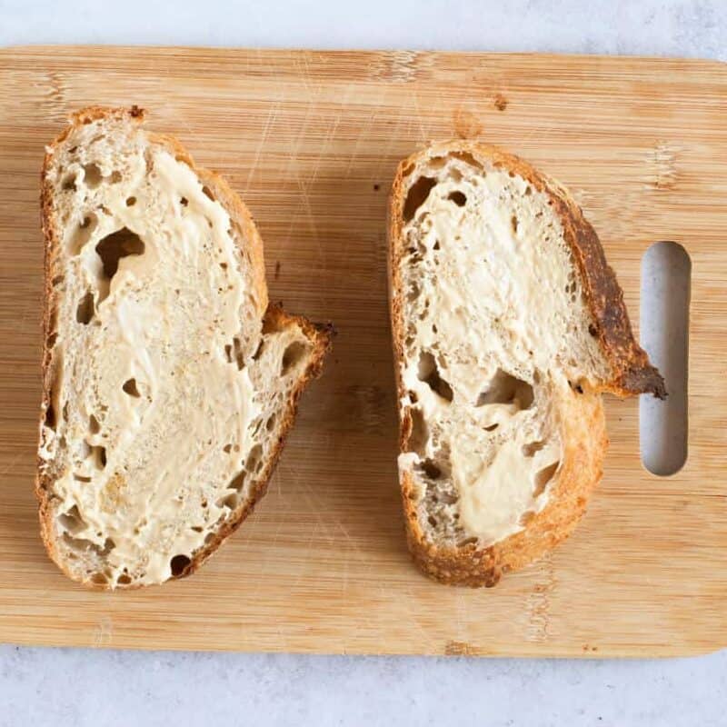 Two slices of bread spread with mayonaise and Dijon mustard.